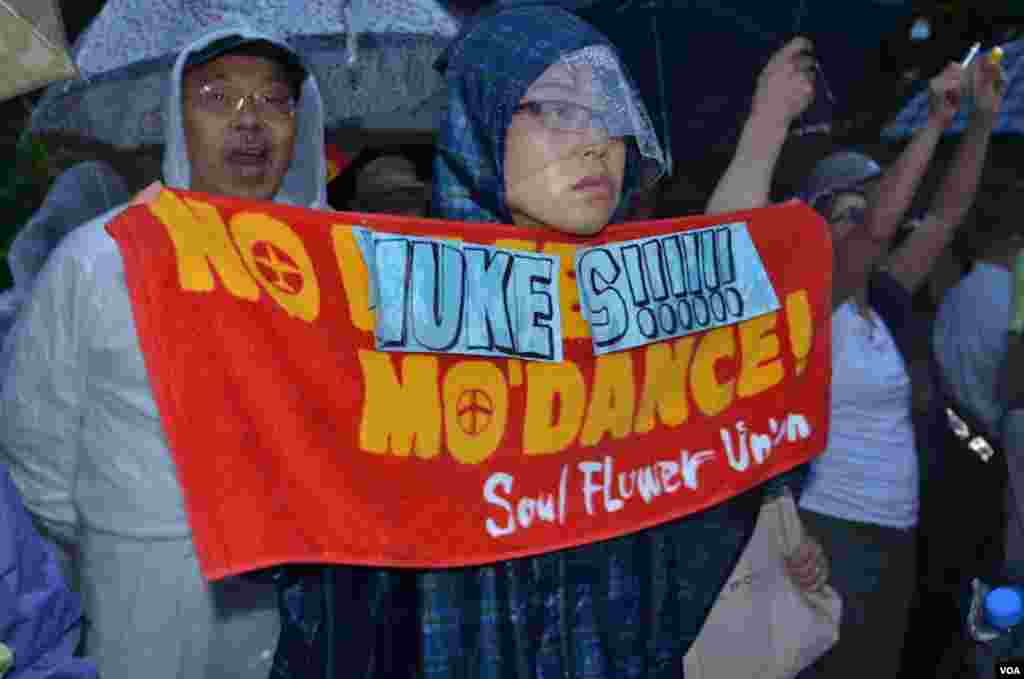 A rain-soaked protester carries an anti-nuclear sign, Tokyo, Japan, July 6, 2012. (S.L. Herman/VOA)