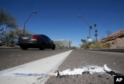 FILE - A vehicle goes by the scene of the March 18, 2018, fatal accident in which a pedestrian was stuck by an Uber vehicle in autonomous mode, in Tempe, Ariz., March 19, 2018.