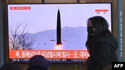 Seorang perempuan berjalan melewati televisi di salah satu stasiun kereta di Seoul, pada 17 Januari 2022, di mana stasiun televisi tersebut menayangkan uji coba peluncuran rudal yang dilakukan oleh Korea Utara. (Foto: AFP/Jung Yeon-je)
