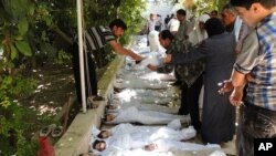 A citizen journalism image provided by the Local Committee of Arbeen which has been authenticated based on contents and AP reporting, shows Syrian citizens trying to identify dead bodies, after an alleged poison gas attack by government forces. There has 