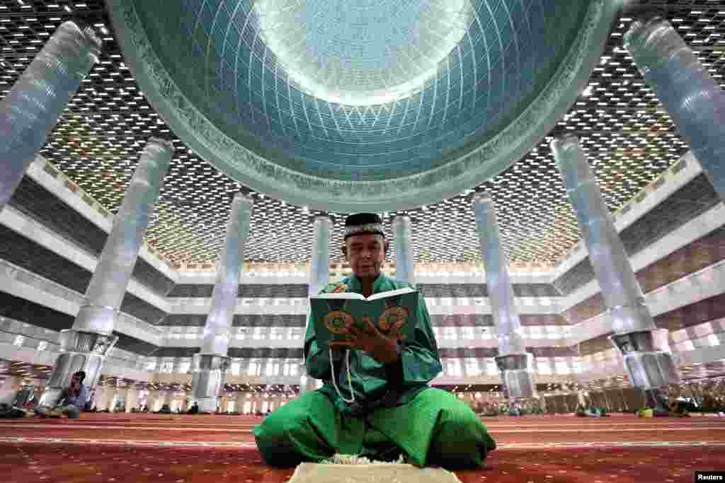 Seorang pria Muslim membaca Al-Qur'an di Masjid Agung Istiqlal selama bulan puasa Ramadan di Jakarta. (Reuters)