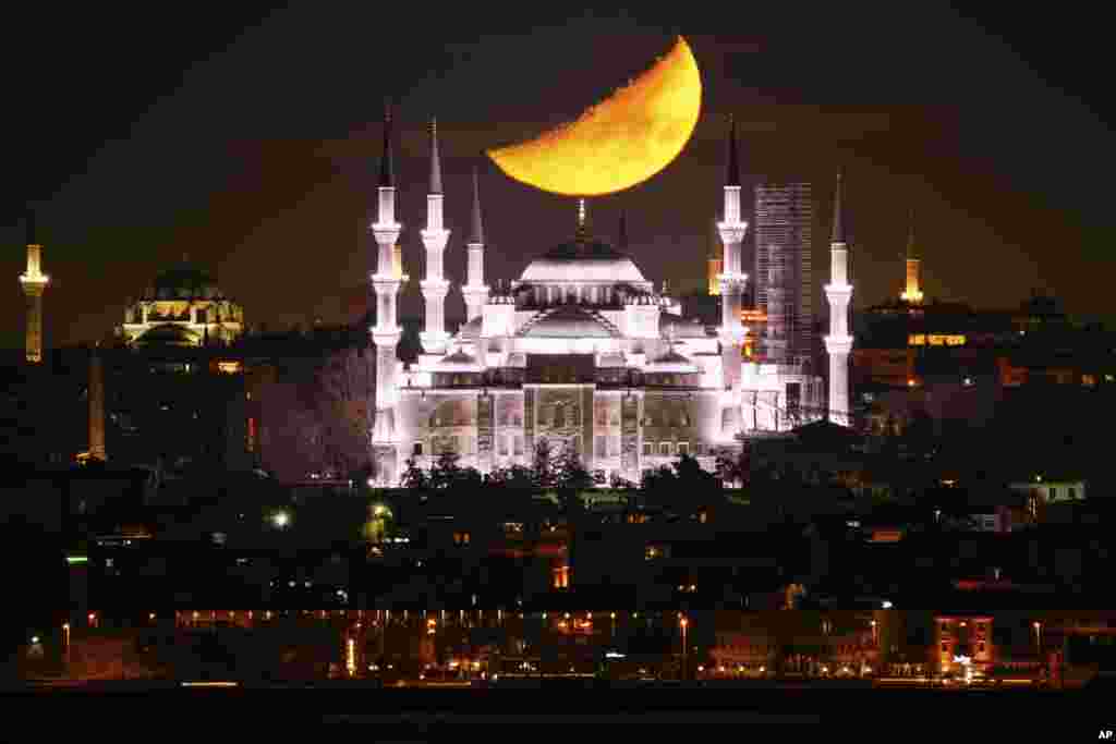 Bulan sabit tampak menjelang terbenam di belakang kubah Masjid Sultanahmet yang dikenal sebagai "Masjid Biru" selama bulan suci Islam Ramadan di Istanbul, Turki. (AP) 