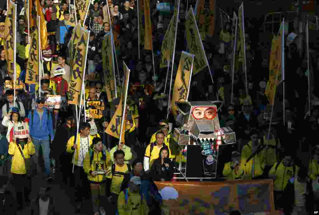 Pengunjuk rasa membawa boneka serigala berwajah Kepala Eksekutif Hong Kong Leung Chun-ying dalam demonstrasi di Hong Kong (1/1). (AP/Kin Cheung)