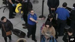 Un agente de la TSA, centro, dirige a los pasajeros a través de un punto de control de seguridad, el lunes 7 de enero de 2019, en el Aeropuerto Internacional John F. Kennedy de Nueva York. El líder de la minoría del Senado, Chuck Schumer, demócrata por Nueva York, sugirió el domingo que el cierre parcial del gobierno está interrumpiendo las operaciones de la Administración de Seguridad del Transporte.