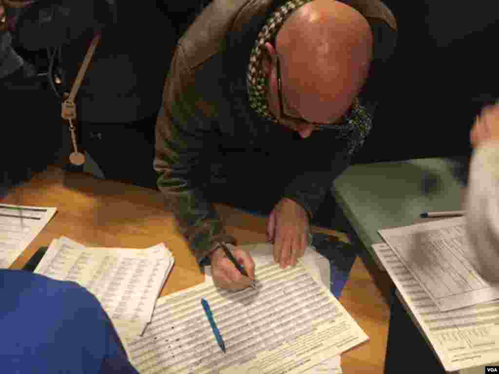 A caucus-goer registers at Hanawalt Elementary School, Des Moines, Iowa, Feb. 1, 2016. (M. Cagler/VOA)