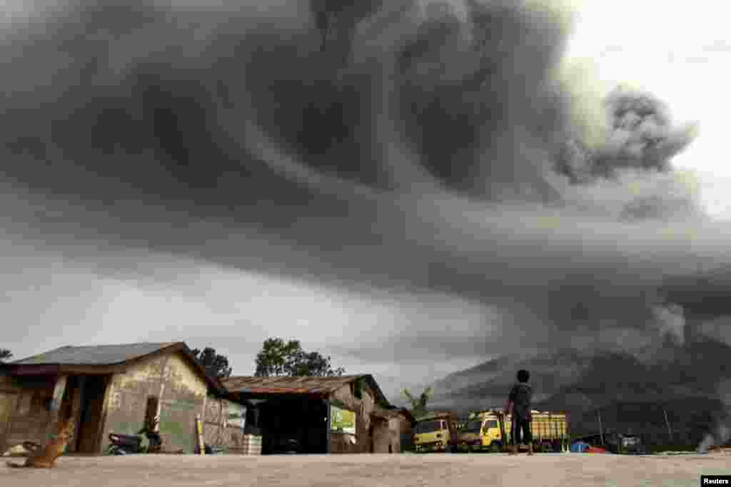 Seorang perempuan warga setempat mengamati Gunung Sinabung yang sedang memuntahkan abu vulkanik, foto diambil dari desa Sibintun di Kabupaten Karo, Sumatra Utara.