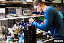 Researcher Ethan Jackson makes adjustments to the prototype mosquito trap in the labs at Microsoft, in this handout photo obtained by Reuters June 30, 2017.