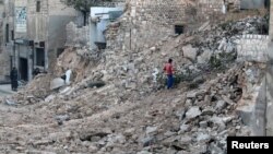 A civilian collects tree branches amid the rubble of a damaged site in the rebel-held besieged Qadi Askar neighborhood of Aleppo, Syria, Nov. 24, 2016. 