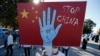 Seorang pengunjuk rasa dari komunitas Uighur yang tinggal di Turki, memegang plakat anti-China saat melakukan protes, 1 Oktober 2020. (Foto: AP)
