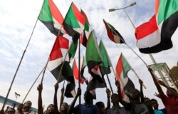 FILE - People wave national flags as they demonstrate against the killing of protesters, who were shot dead when security forces broke up a rally in Khartoum, Sudan, Aug. 1, 2019.
