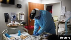 Christopher Peter, 32, seorang spesialis pernapasan, memeriksa pasien saat profesional medis merawat orang yang terinfeksi Covid-19 di United Memorial Medical Center di Houston, Texas, AS, 12 November 2020. (Foto: Reuters)