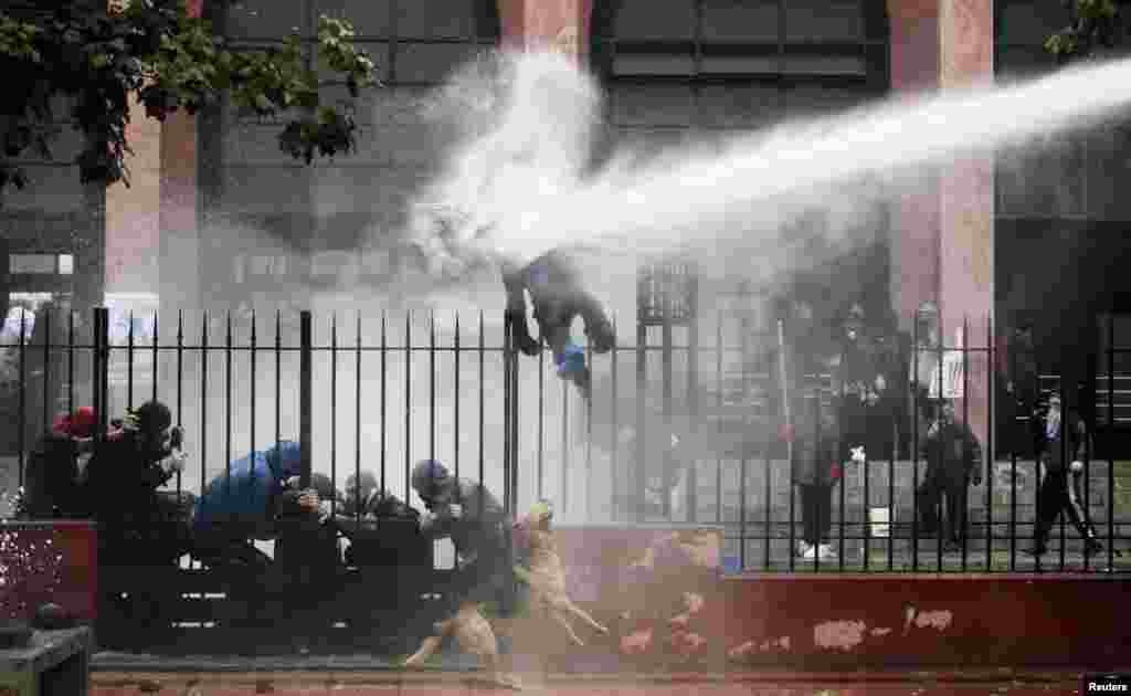 Seorang mahasiswa terkena semprotan air oleh polisi anti huru hara selama protes menuntut perbaikan sistem pendidikan publik di Santiago, Chili.