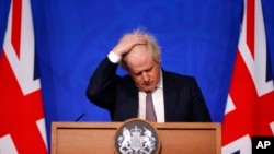 Perdana Menteri Inggris Boris Johnson bereaksi ketika berbicara dalam konferensi pers di London, pada 27 November 2021. (Foto: Pool via AP/Hollie Adams)