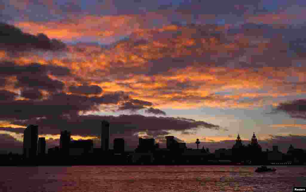 A river pilot boat travels along the River Mersey as the sun rises behind the skyline of Liverpool, Britain.