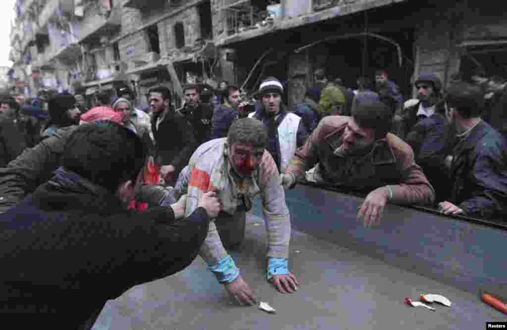 People help a wounded person after a missile hit Aleppo's al-Mashhad district, Syria, January 7, 2013.