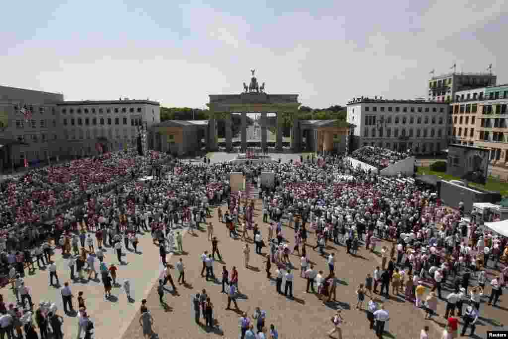 Invited guests are entertained by violinist David Garrett as they await the arrival of U.S. President Barack Obama in front of the Brandenburg Gate in Berlin June 19, 2013.