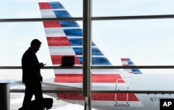 FILE - A passenger talks on the phone as American Airlines jets sit parked at their gates at Washington's Ronald Reagan National Airport, Jan. 25, 2016.