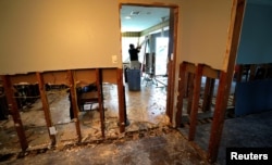 FILE - A man tears out Hurricane Harvey flood damage from a home in southwestern Houston, Texas, Sept. 2, 2017.