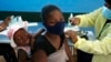 FILE - A mother receives her Pfizer vaccine against COVID-19 in Diepsloot Township near Johannesburg, Oct. 21, 2021. 