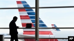 ARSIP – Seorang penumpang tampak berbicara di telepon dengan latar belakang American Airlines yang terparkir dekat Bandara Nasional Ronald Reagan, Washington, D.C. 25 Januari 2016 (foto: AP Photo/Susan Walsh, Arsip)