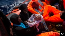 Migran dari Nigeria, salah satunya menggendong bayi, berhasil diselamatkan saat ditemukan terapung-apung di perairan lepas pantai Sabratha, Libya, 28 Agustus 2019. 