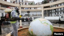 Mfanyakazi akiwa katika mavazi ya kujikinga na virusi vya corona akiweka dawa ya kuzuia virusi vya corona kusambaa katika bustani katikati ya mji baada ya mlipuko wa COVID-19 jijini Algiers, Algeria Machi 23, 2020. 