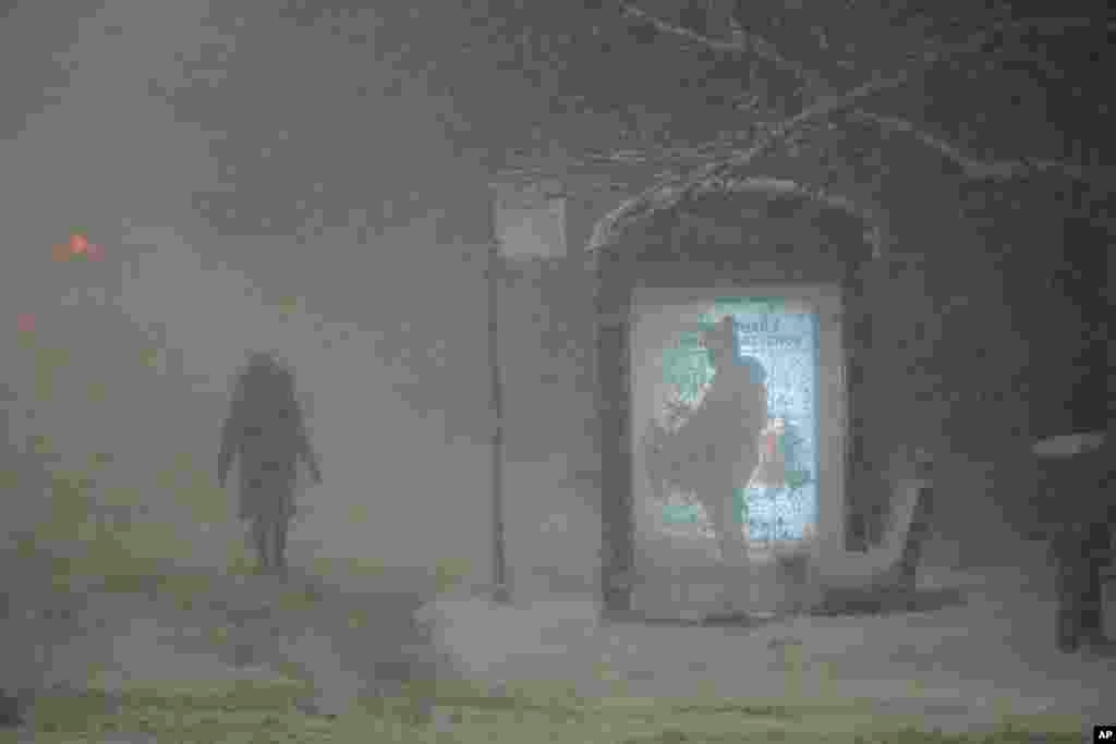 A woman walks to a bus stop on Martin Luther King Jr. Drive during the pre-dawn hours in Chicago.&nbsp;A major winter storm brought a mix of rain, freezing rain and snow to the middle section of the United States as airlines canceled hundreds of flights.