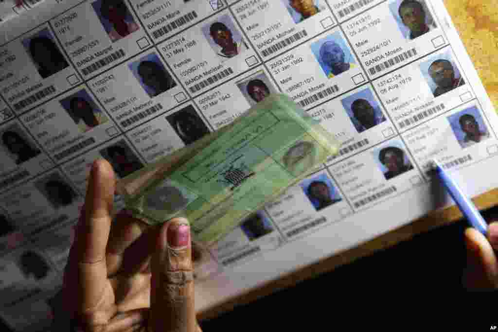 An election official verifies information on the electoral roll during presidential election day in Lusaka, Jan. 20, 2015.