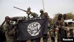 Des membres de l'armée nigériane tiennent le drapeau de Boko Haram à Damasak, Nigeria, le 18 mars 2015.