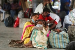 FILE - Migrant laborers wearing masks as a precaution against the coronavirus wait for transportation in Jammu, India, April 16, 2021.