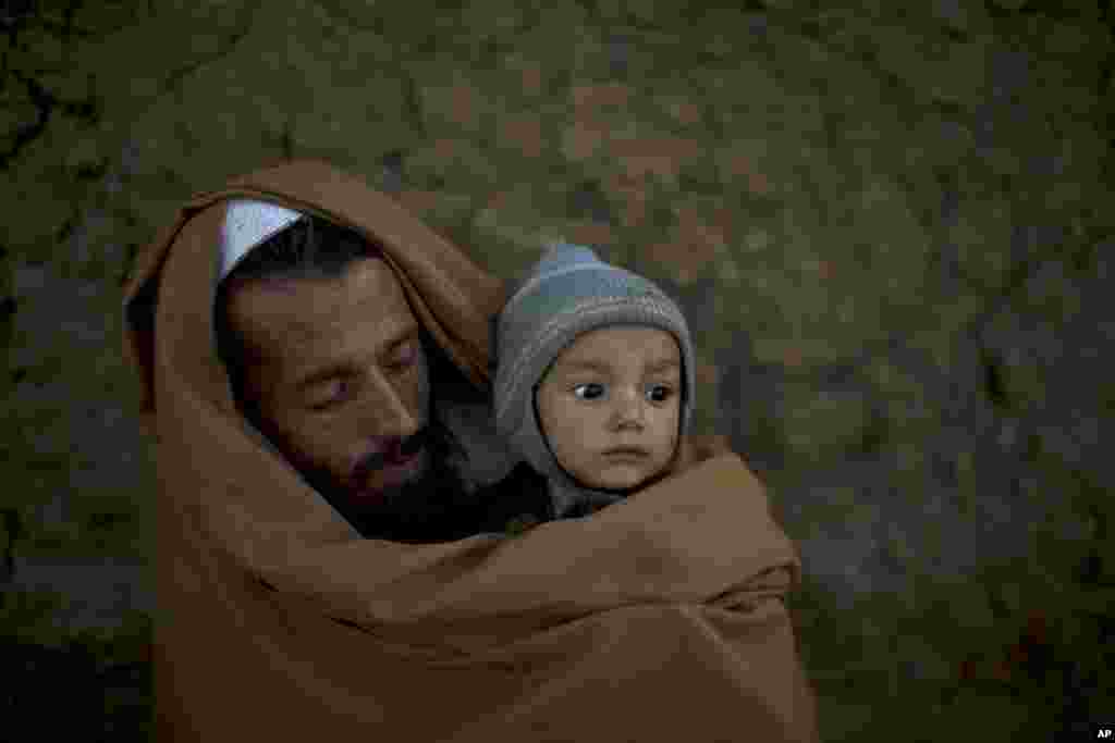 Pakistani Ibrahim Mohammed, 42, who was displaced with his family from Pakistan's tribal region of Mohmand Agency due to fighting between the Taliban and the army, wraps himself and his son Mashal, 1, with a shawl to avoid the evening cold, while sitting in front of his home in a poor neighborhood on the outskirts of Islamabad.