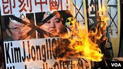 Warga Korsel membakar poster pemimpin Korut Kim Jong-il dan Kim Jong-un dalam protes di Seoul, 28 Desember 2010.
