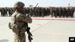 FILE - In this July 24, 2016 file photo, a U.S. military personal stands guard during a graduation ceremony for Afghan troops, in Lashkargah, capital of southern Helmand province, Afghanistan. 