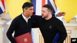 Perdana Menteri Inggris Rishi Sunak, kiri, memeluk Presiden Ukraina Volodymyr Zelenskyy setelah menandatangani dokumen di Kyiv, Ukraina, Jumat, 12 Januari 2024. (AP Photo/Efrem Lukatsky)