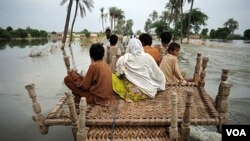 Penduduk desa Pakistan menyeberangi banjir di daerah Baseera, Pakistan, 24 Agustus 2010.
