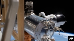 This July 1, 2020 photo made available by NASA shows the SpaceX Crew Dragon, right, docked to the International Space station, during a spacewalk conducted by astronauts Bob Behnken and Chris Cassidy. On Wednesday, July 29, 2020, SpaceX and NASA…