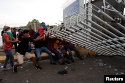A group of men part of a caravan of thousands of migrants from Central America en route to the U.S, pull down the border gate with the intention to carry on their journey, in Tecun Uman, Guatemala, Oct. 28, 2018.