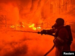 Seorang petugas pemadam kebakaran memadamkan abi di sebuah lokasi di Kharkiv, Ukraina usai serangan pesawat nirawak Rusia di tengah invasi Rusia ke Ukraina, Sabtu, 4 Mei 2024. (Foto: Vitalii Hnidyi/Reuters)