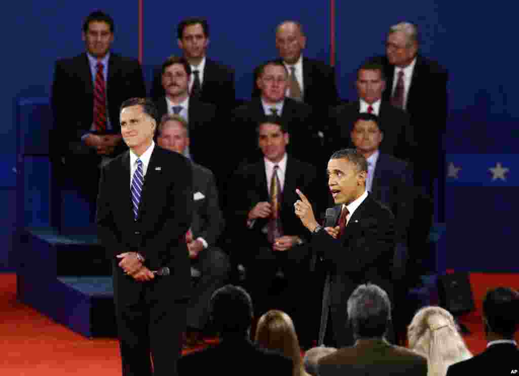 Presiden Barack Obama berbicara sementara kandidat dari Partai Republik, Mitt Romney, menunggu gilirannya. 