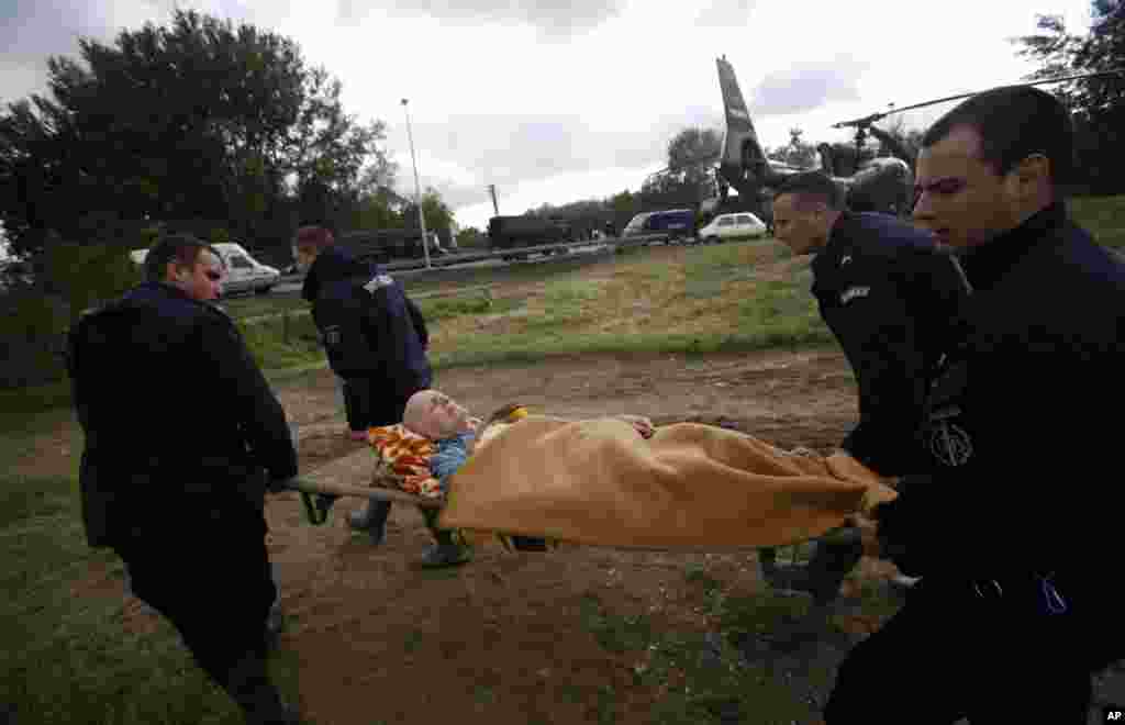 Polisi menggotong seorang pria dari helikopter militer dalam evakuasi banjir di Obrenovac, Serbia (17/5). (AP/Darko Vojinovic)