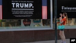 Seorang wanita memotret poster penyambutan Presiden AS, Donald Trump, dan Presiden Rusia, Vladimir Putin, di sebuah toko di pusat kota Helsinki, 14 Juli 2018 (foto: AP Photo/Markus Schreiber)