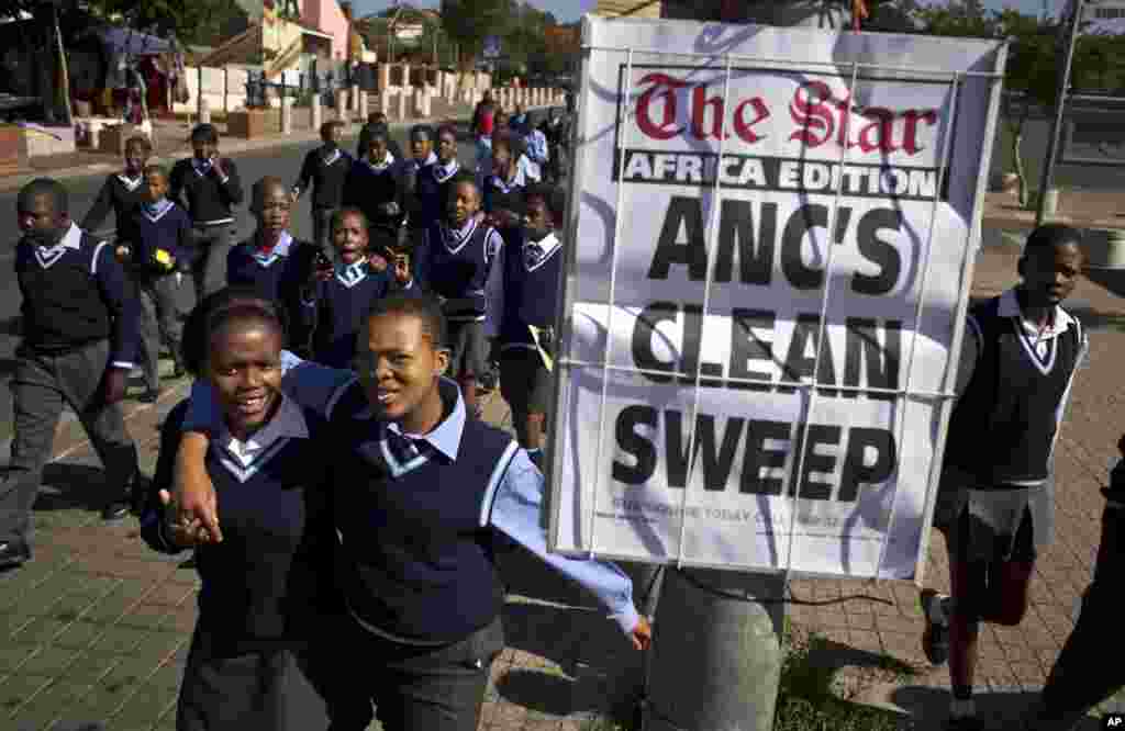 Schoolchildren walk past a newspaper placard reporting the election victory of Jacob Zuma's African National Congress (ANC) party, based on preliminary results, in the Soweto township of Johannesburg, South Africa, May 9, 2014.