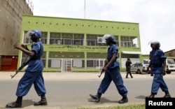 FILE - Riot policemen are seen walking outside the Radio Publique Africaine broadcasting studio in Burundi's capital, Bujumbura. Human Rights Watch is calling for a special envoy to Burundi and the exploring of a possible deployment of an international police force.