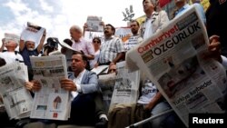 Aktivis kebebasan pers membaca surat kabar oposisi Cumhuriyet selama demonstrasi solidaritas dengan anggota surat kabar yang dipenjara di luar gedung pengadilan, di Istanbul, Turki, 28 Juli 2017. (Foto: Reuters/Murad Sezer)