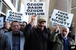 Turkish journalists cover their mouths with black ribbons before the trial of Can Dundar, the editor-in-chief of opposition newspaper Cumhuriyet and Erdem Gul, the paper's Ankara representative, outside the courthouse in Istanbul, April 1, 2016.