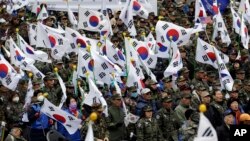 Veteran perang dan anggota kelompok-kelompok konservatif memegang bendera nasional dalam demonstrasi yang menyerukan persatuan antara dua Korea, di Seoul (1/3). (AP/Lee Jin-man)