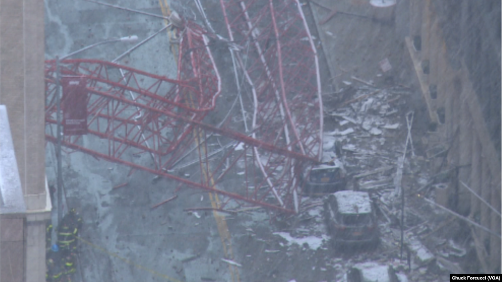 Une grue est tombée du haut d’un immeuble et s’est écrasée au sol contre des véhicules, causant au moins un mort et trois blessés dans une rue de New York City, 5 février 2016. Chuck Forcucci (VOA New York Bureau)