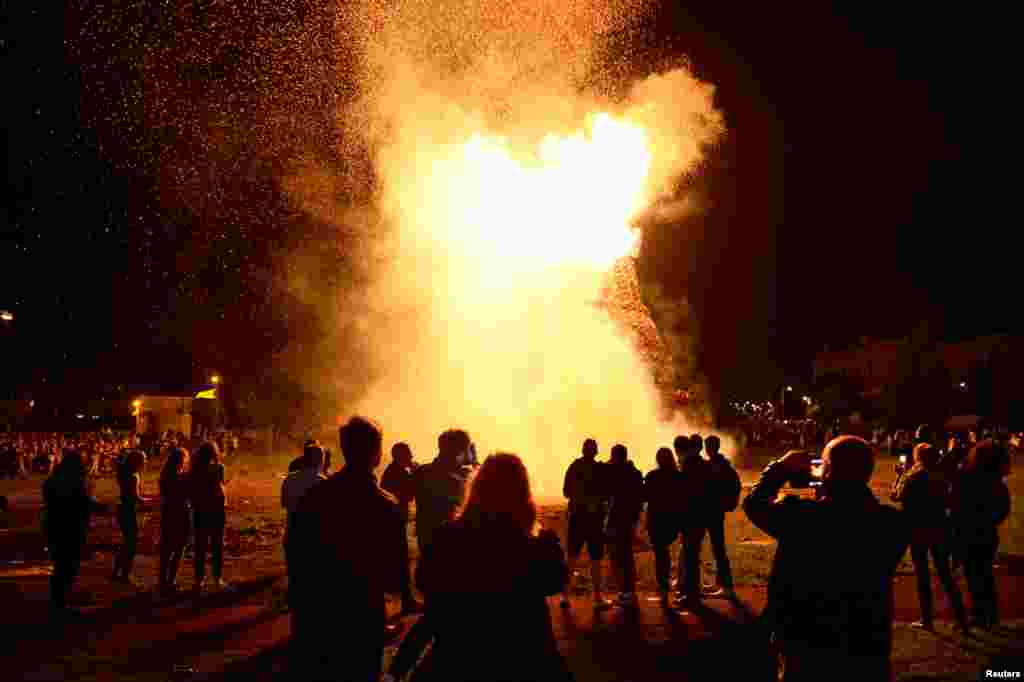 People gather to watch a bonfire burn in the Shankill Road area ahead of the Twelfth of July celebrations held by members of the Orange Order in Belfast, Northern Ireland.
