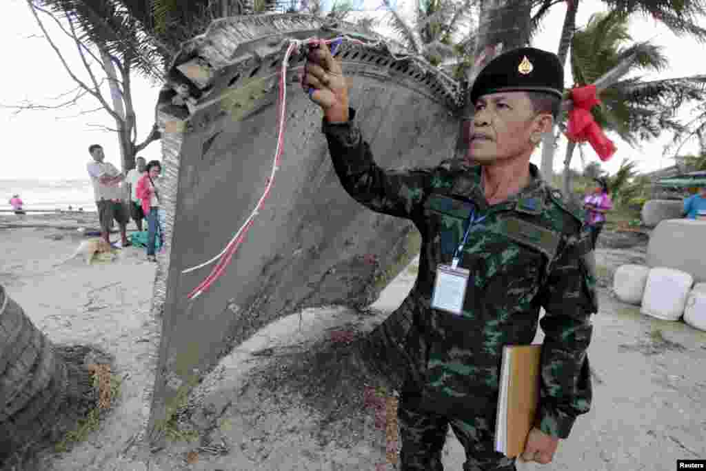 Thai army soldier inspects a piece of suspected plane wreckage which has been found off the coast of southern Thailand in Nakhon Si Thammarat province, Jan. 24, 2016.
