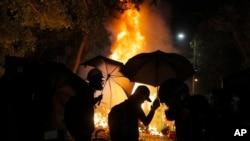 Students walk by a fire during a clash with police at the Chinese University in Hong Kong, Nov. 12, 2019. 
